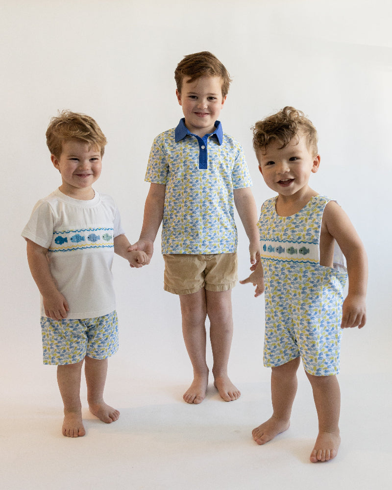 Three young boys wearing matching outfits with blue and yellow patterns on a white background